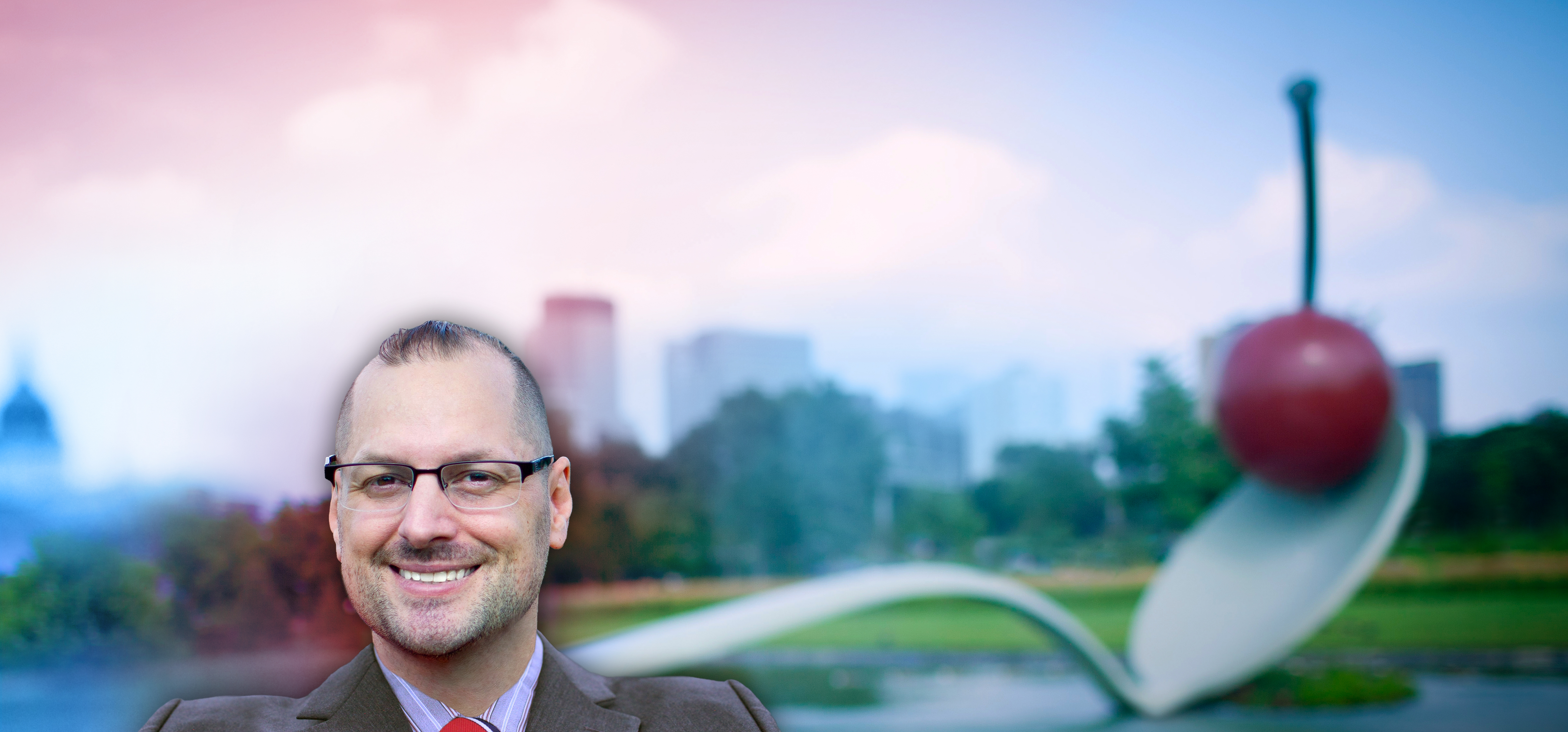 Image of Eric M. Kelsey, Minnesota, a man who is smiling and wearing glasses, a gray suit, and a red tie.